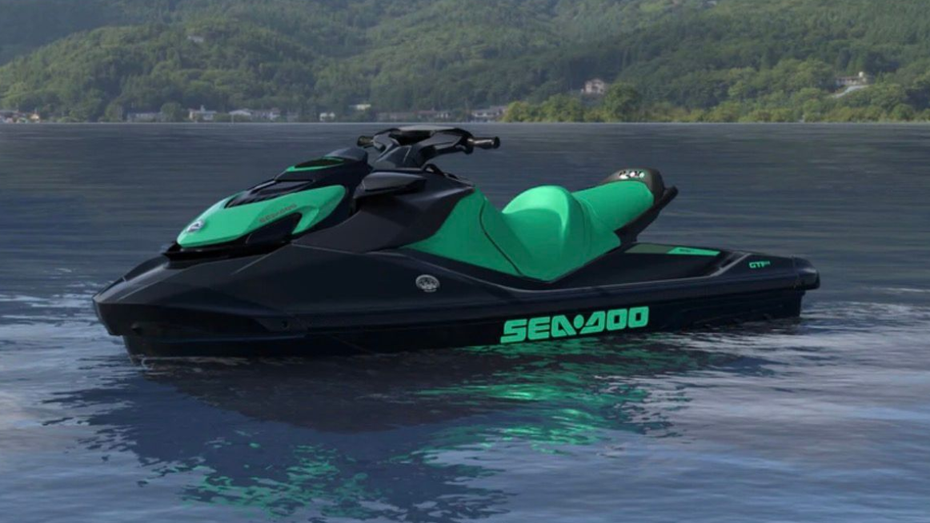 Green and black Sea-Doo jet ski floating on calm water near a forested shoreline