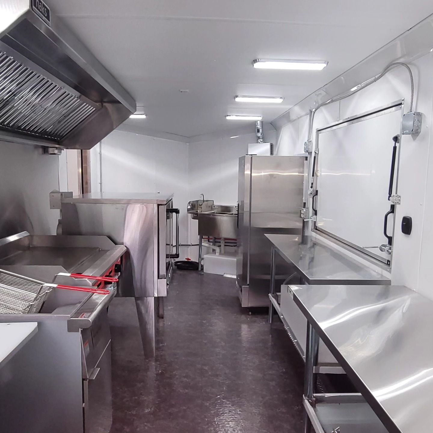 Interior view of a food truck kitchen with stainless steel appliances, including a deep fryer and work surfaces.