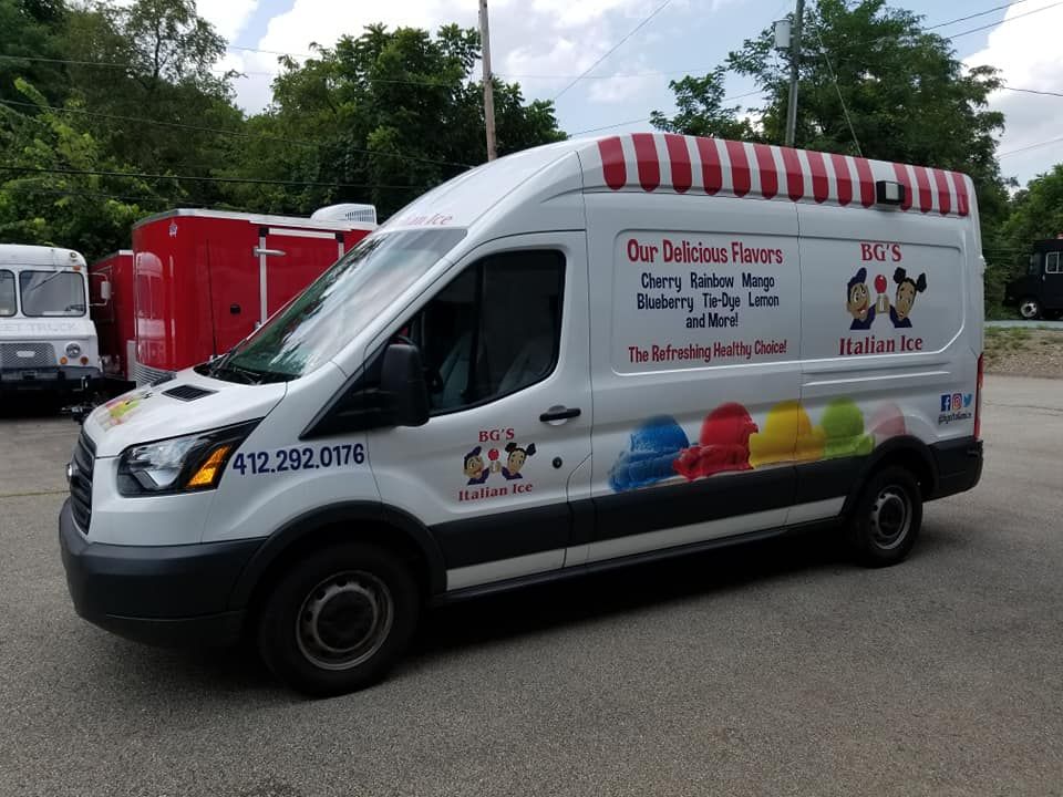 White ice cream van with red awning, colorful scoops, and text: 