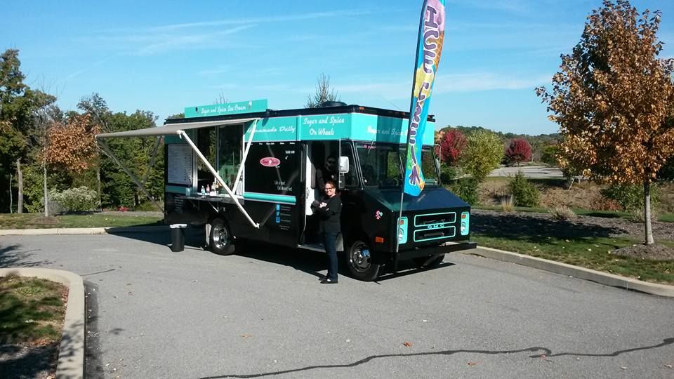 Food truck with turquoise accents and a person standing in front on a sunny day.