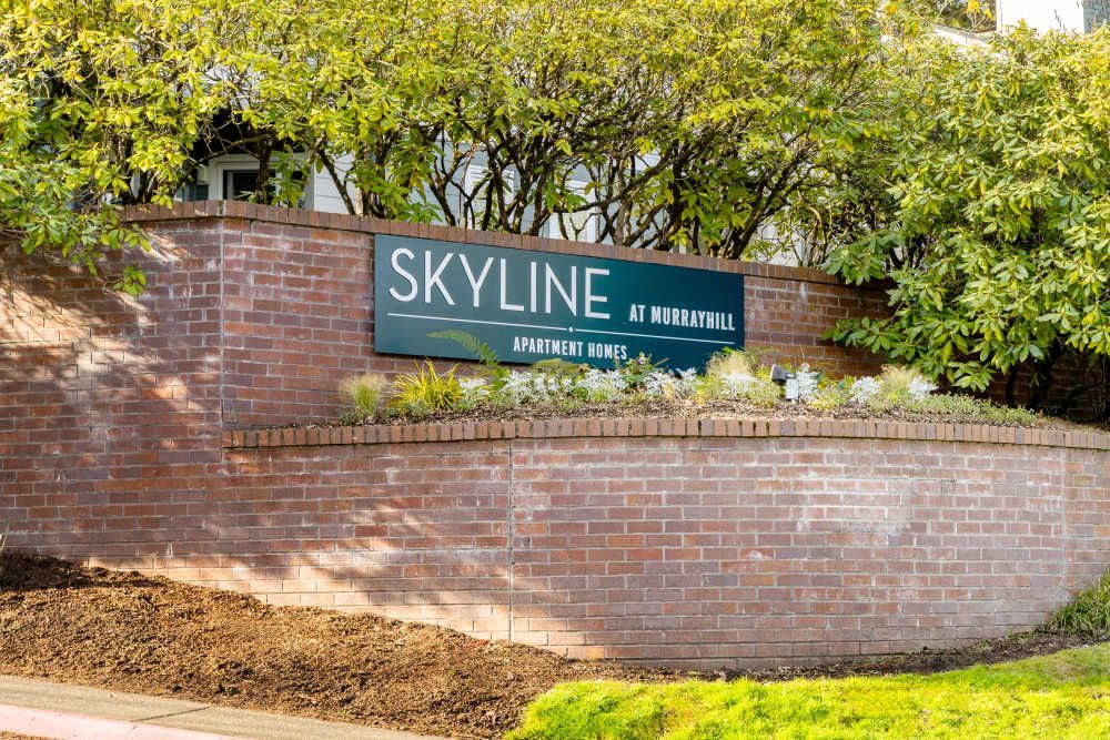Exterior sign on a brick wall reading 'Skyline at Murrayhill' with greenery.