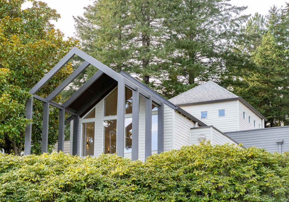 Modern apartment building exterior with glass entry and surrounding greenery.