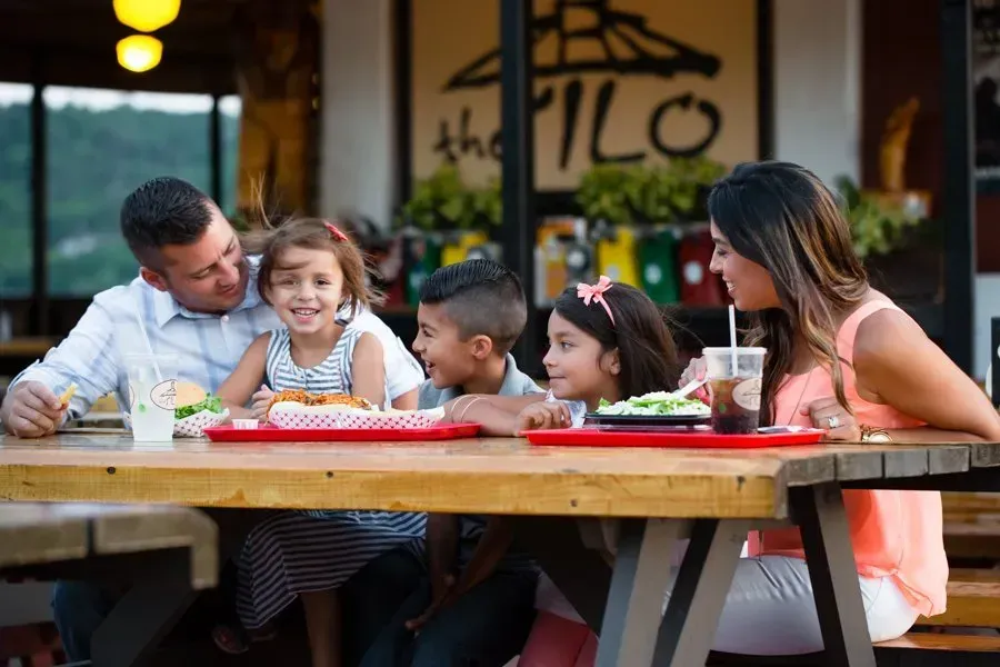 A family is sitting at a picnic table eating food.