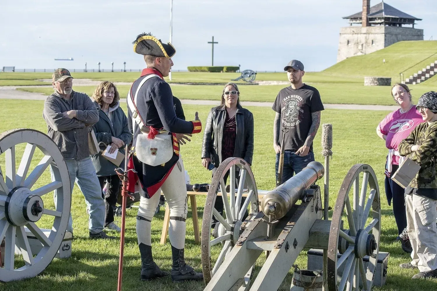 A group of people are standing around a cannon in a field.