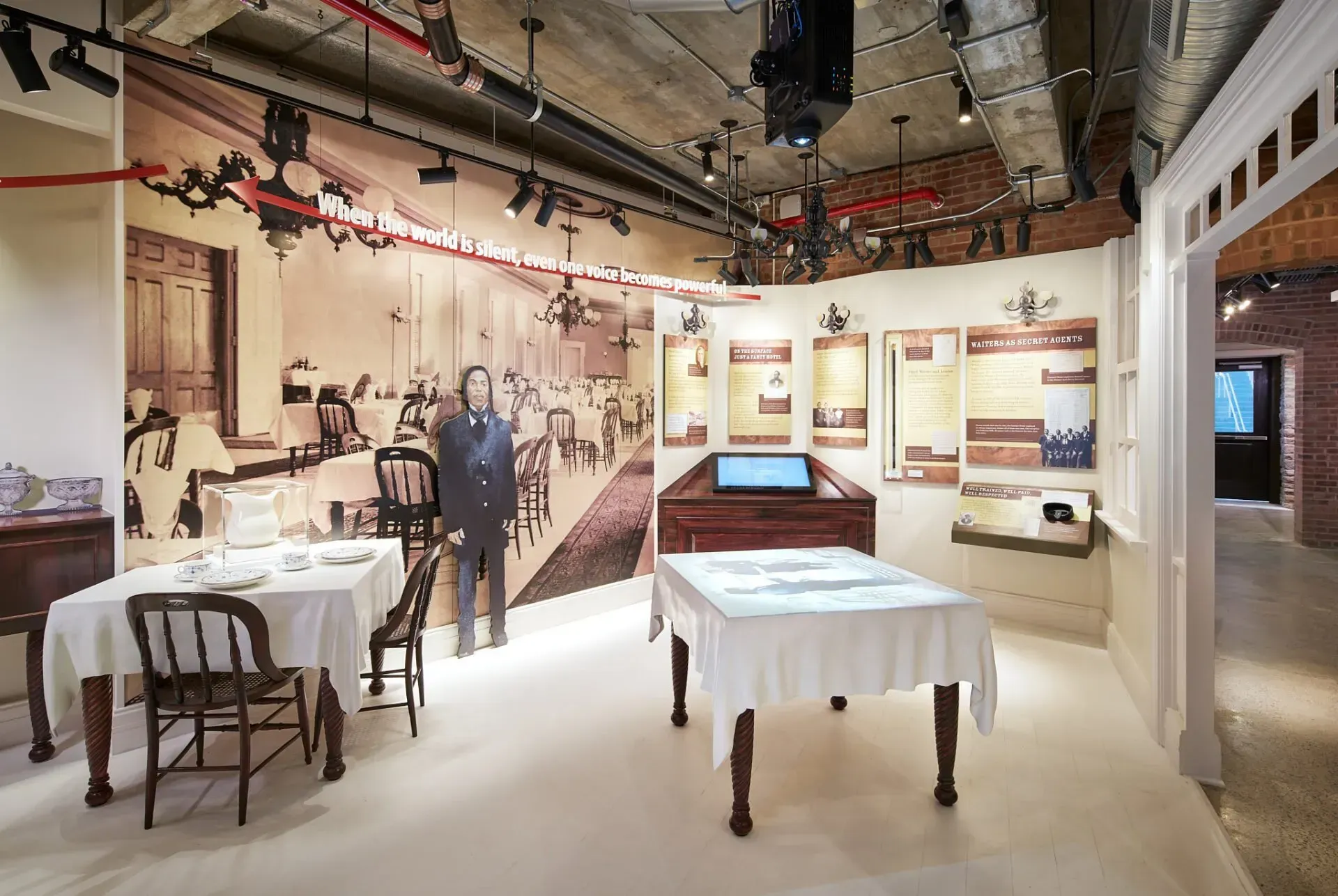 A room with tables and chairs and a man standing in the background