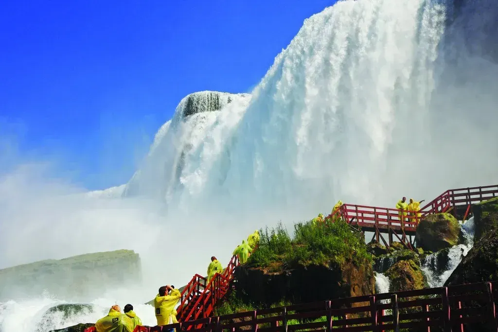 A group of people are standing on a bridge overlooking a waterfall.