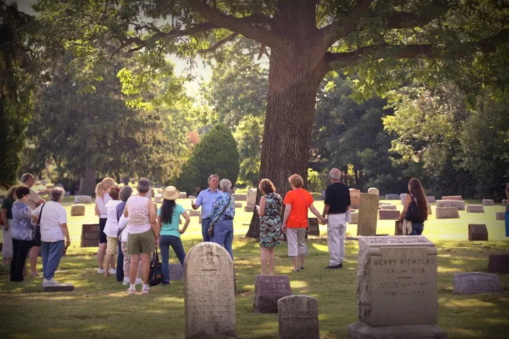 A group of people are standing in a cemetery looking at graves