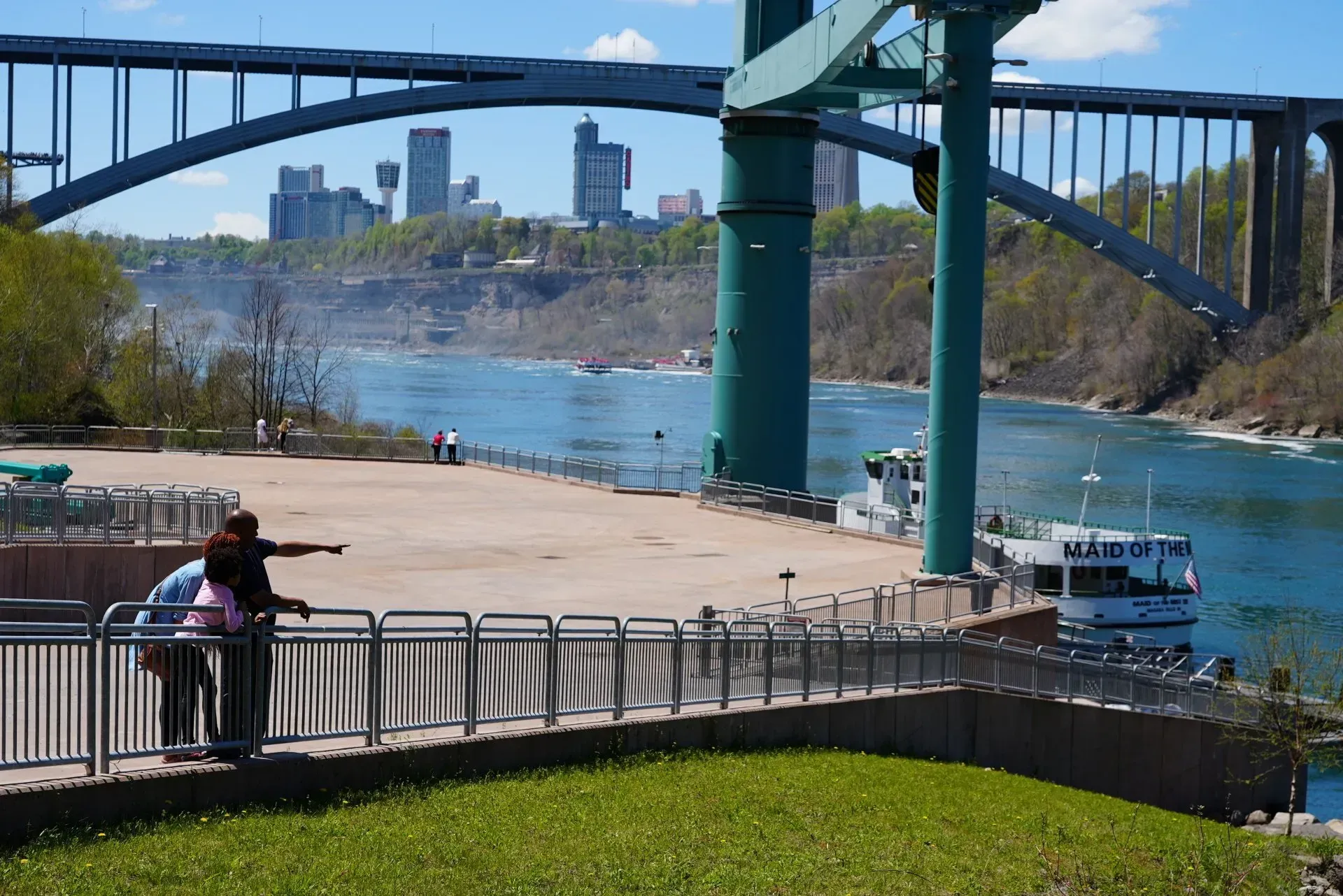 A couple standing under a bridge overlooking a body of water