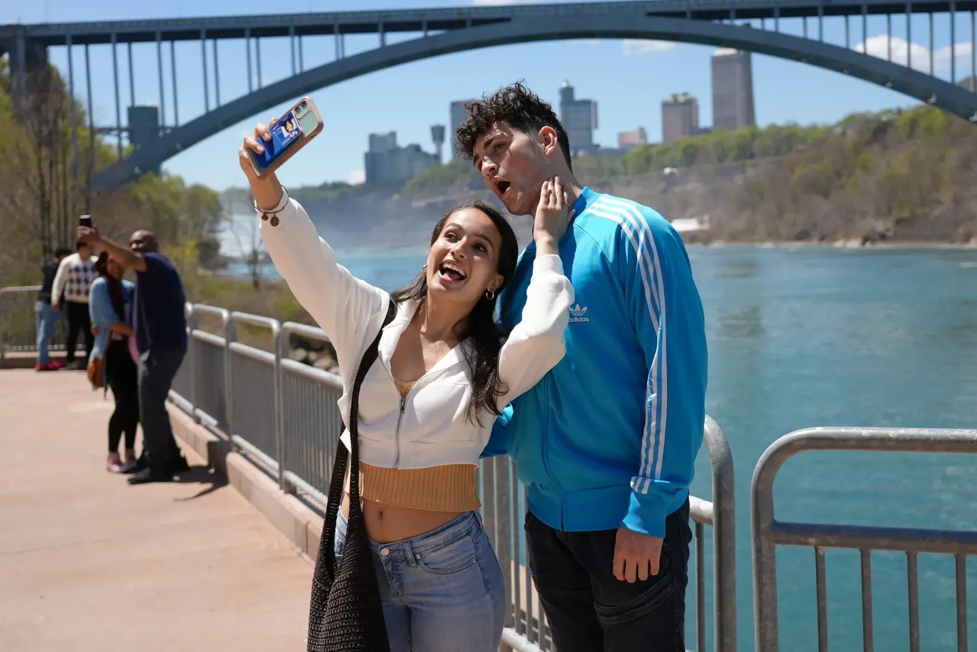 A man and a woman are taking a selfie on a bridge.