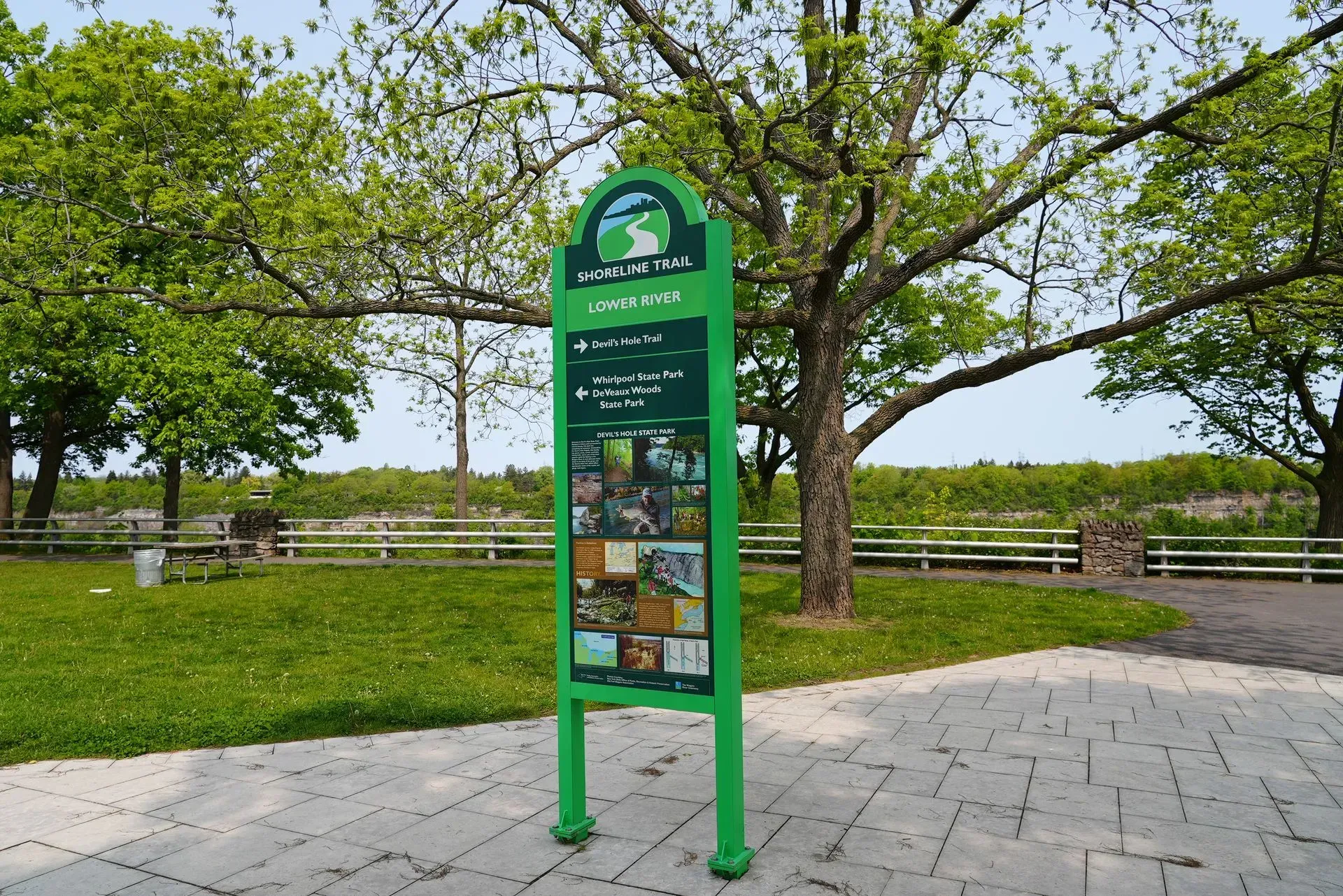 A green sign in a park with trees in the background