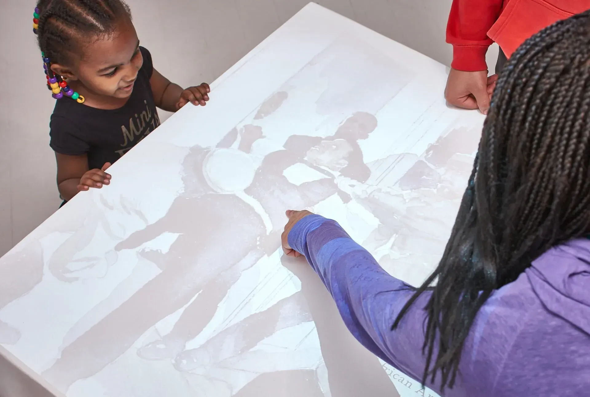A little girl is looking at a picture on a table.