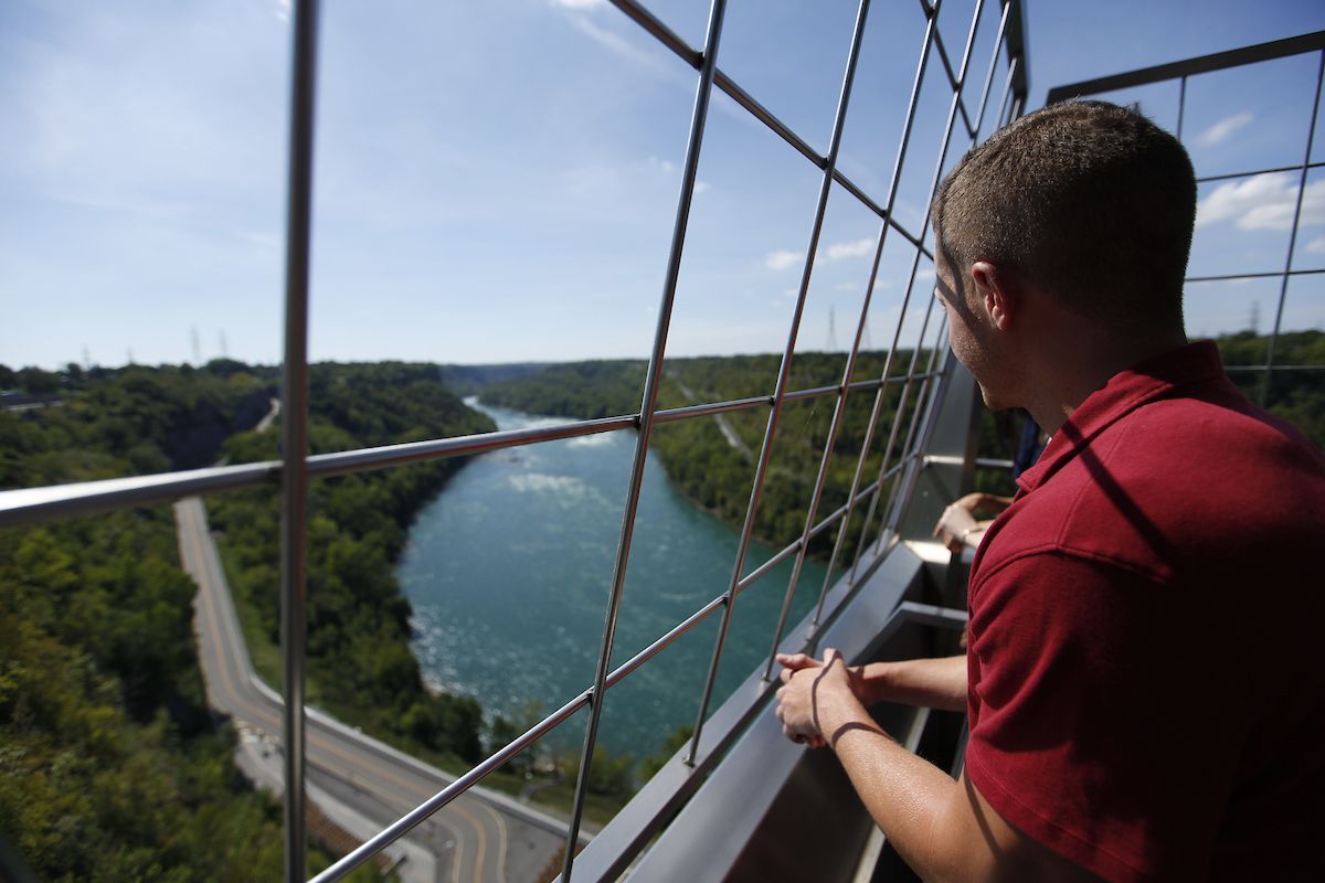 A man in a red shirt is looking out over a river