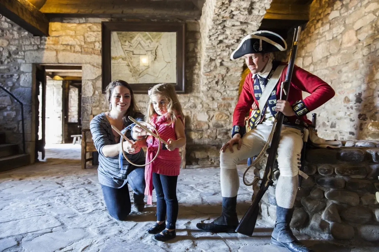 A woman and a little girl are kneeling next to a man in a military uniform.