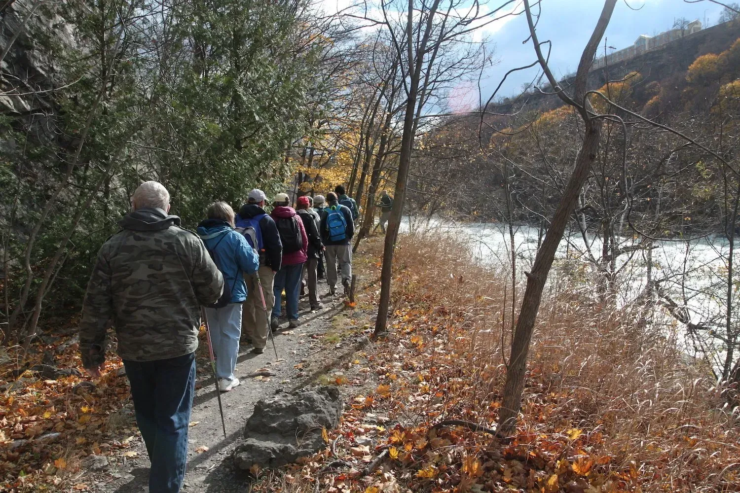 A group of people are walking down a path next to a river