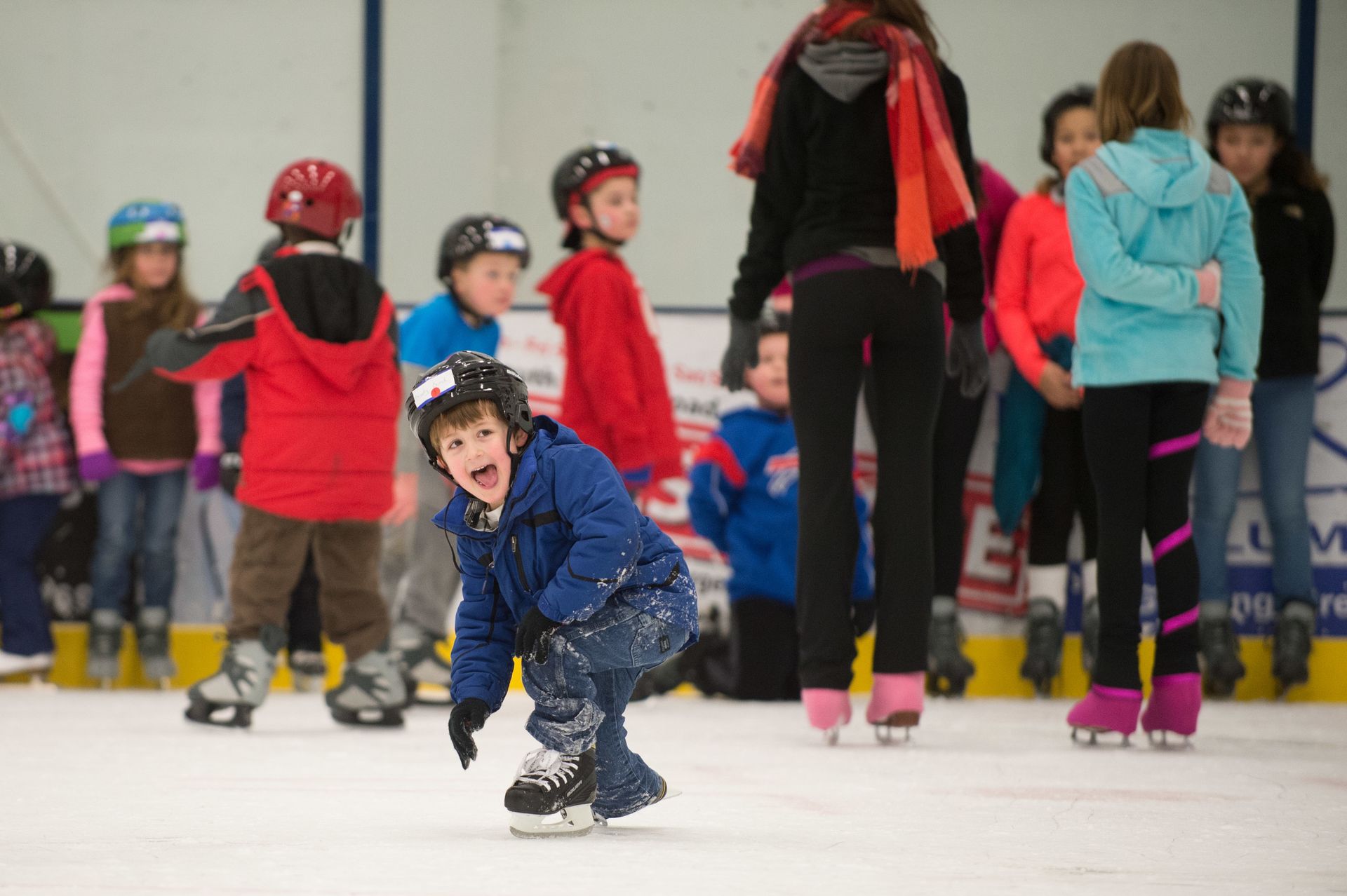 A group of children are ice skating on a rink.