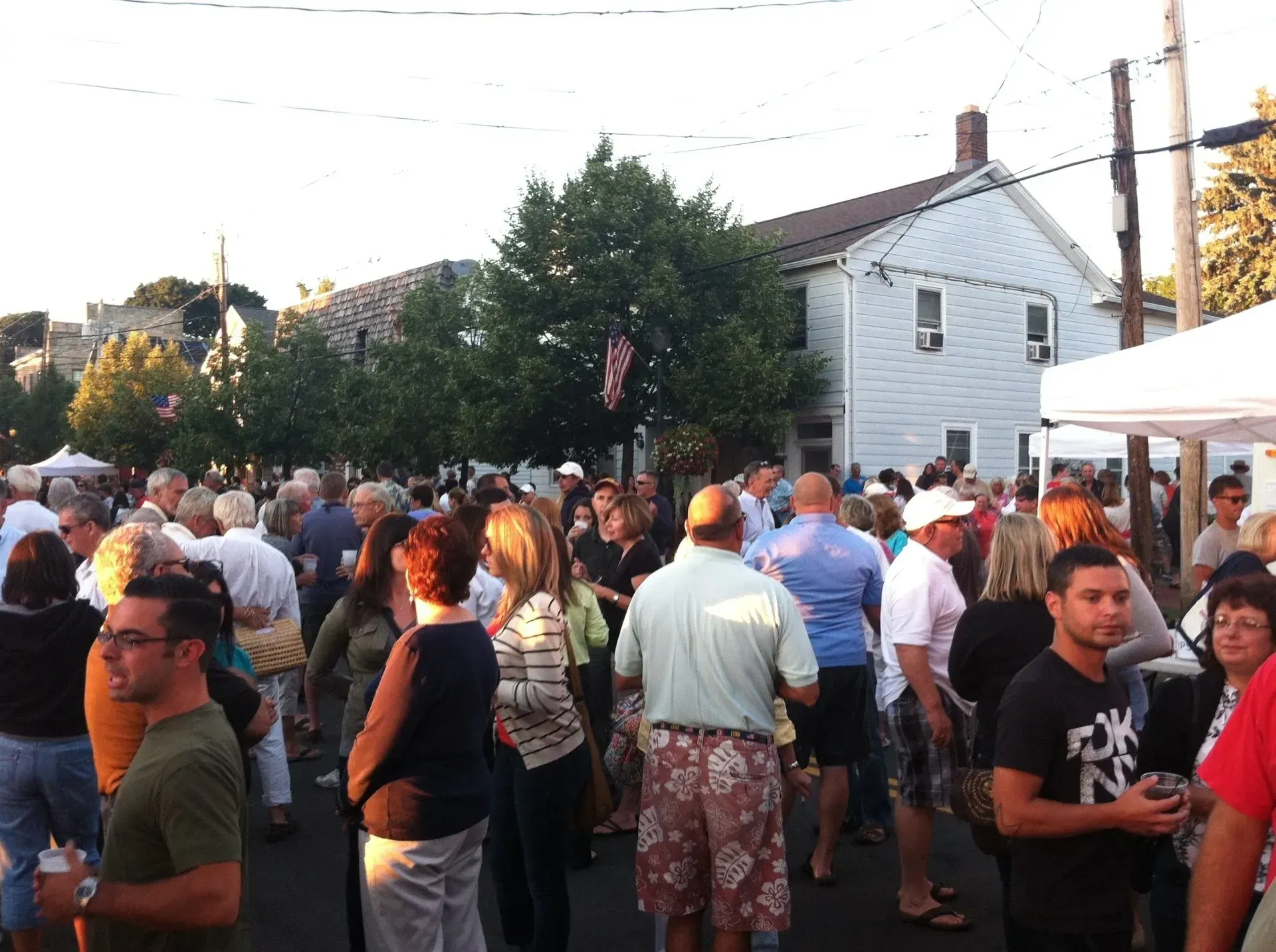 A crowd of people are gathered in front of a white house