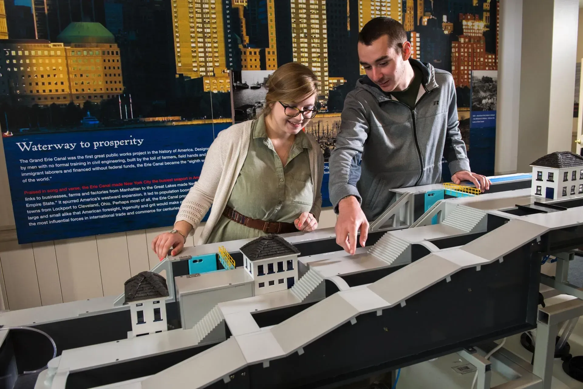 A man and a woman are looking at a model of a city.