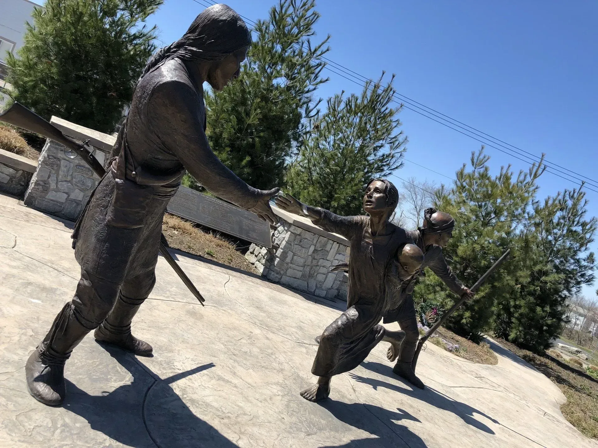 A bronze statue of a man and two children holding swords.