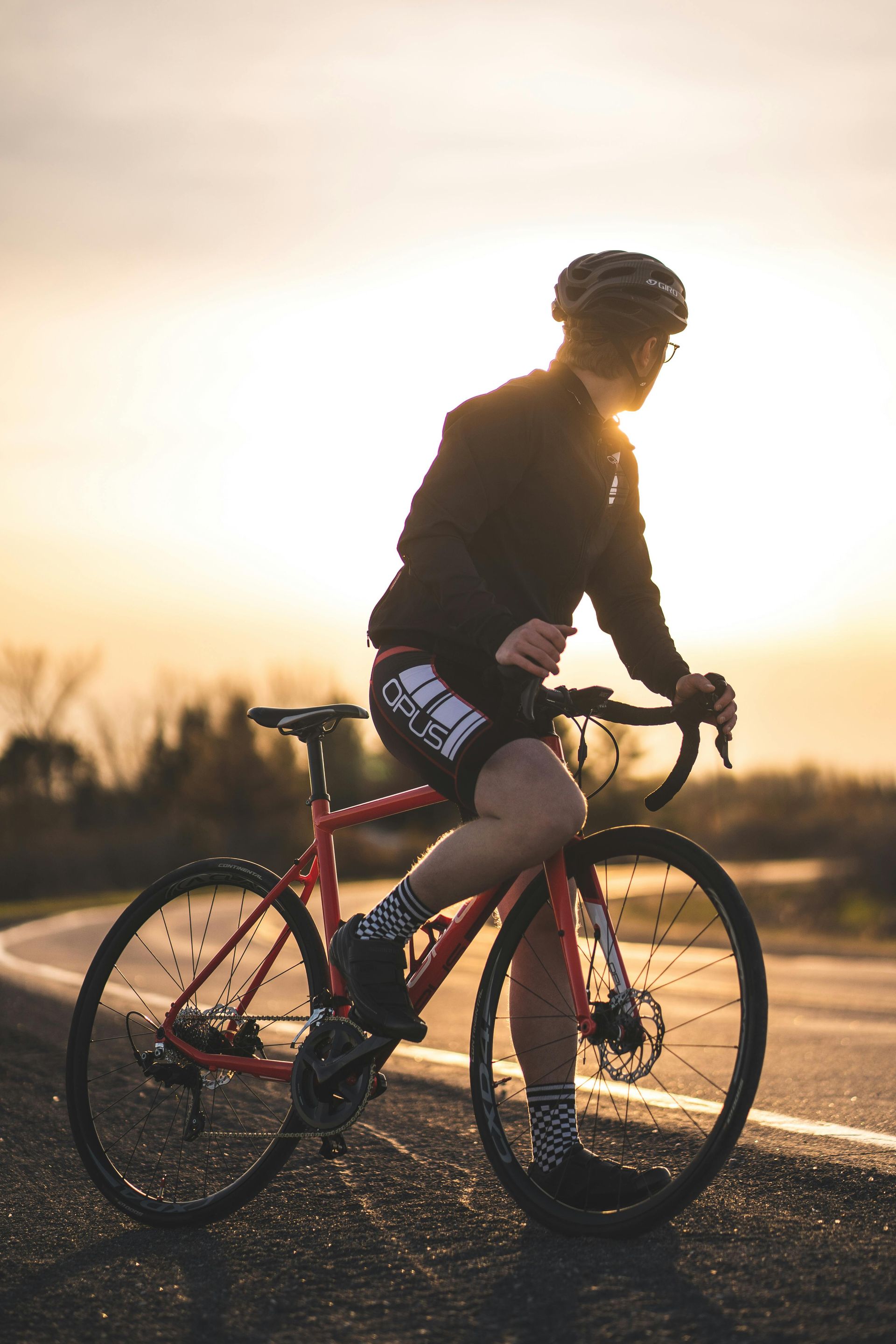 A person is riding a bike down a road at sunset.