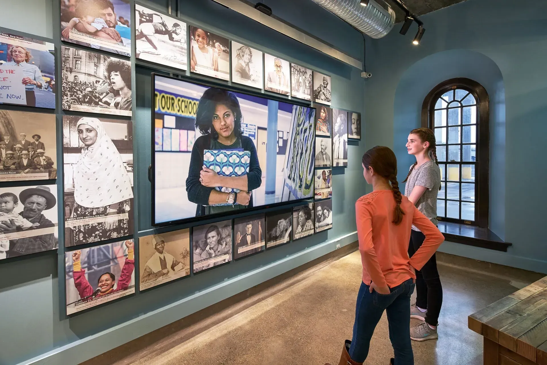 A group of people are standing in front of a wall of pictures.