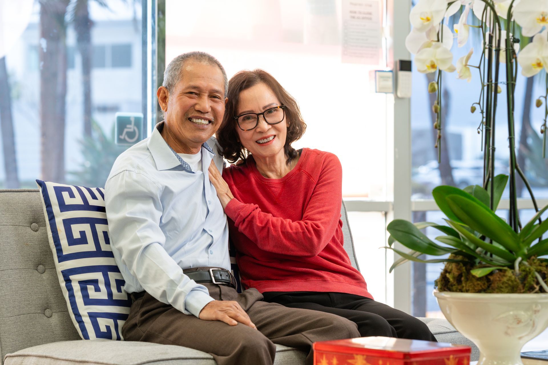 An older person puts a coin into a white piggy bank on a wooden table.