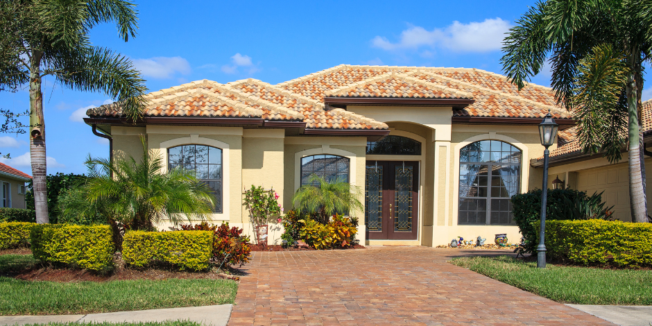 A house with a brick driveway and palm trees in front of it