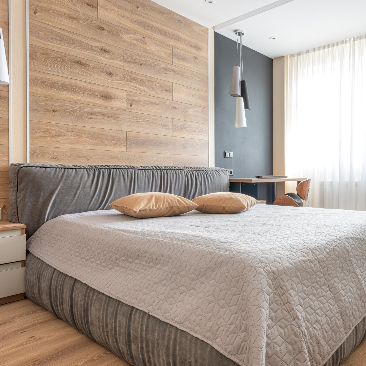 A bedroom with a large bed and a wooden wall behind it.
