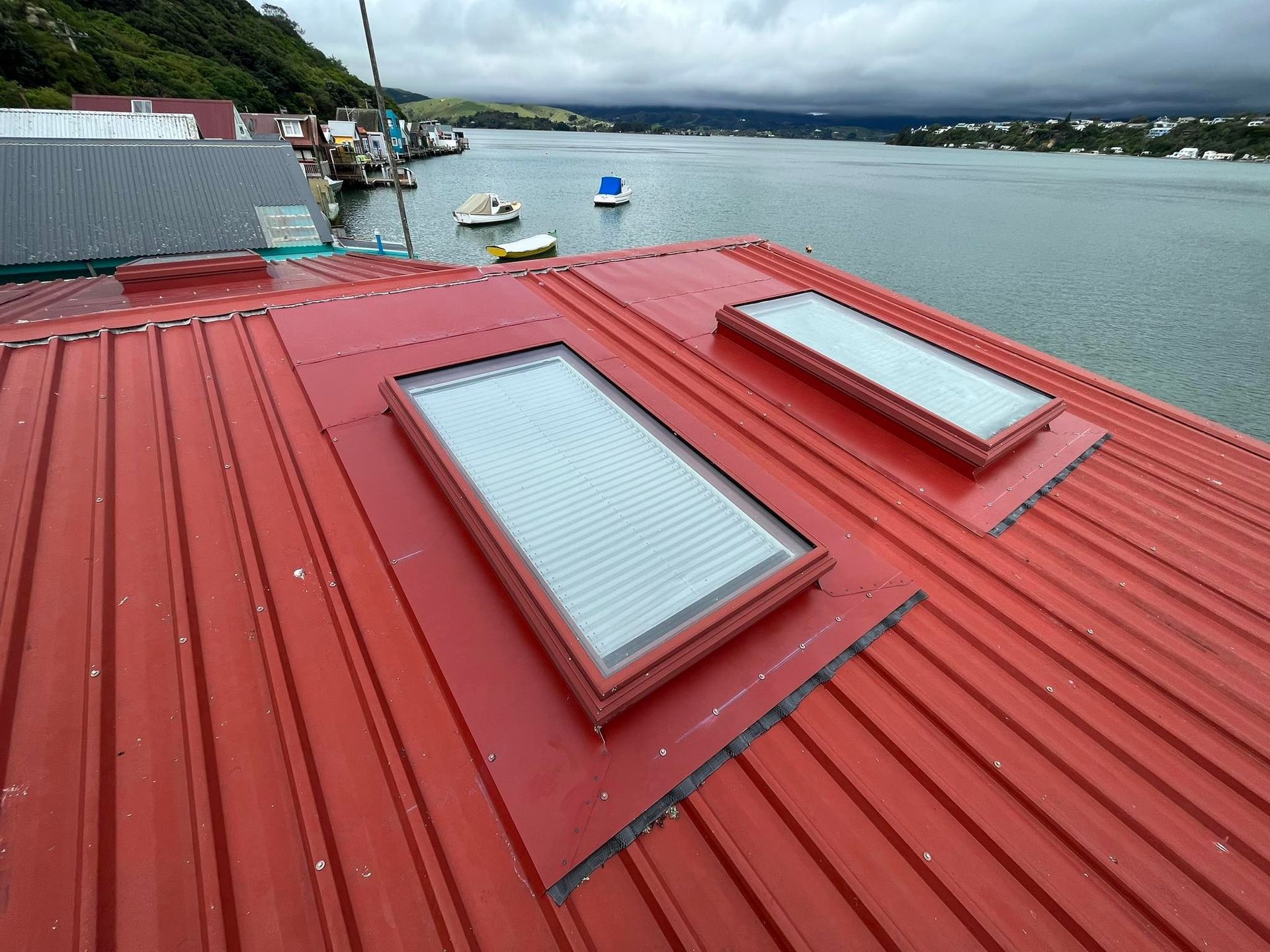 A man is standing on top of a roof with a skylight.