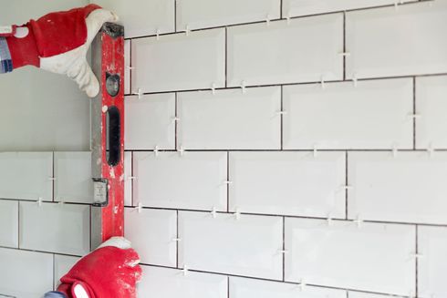 A person is using a level to check the level of a tiled wall.