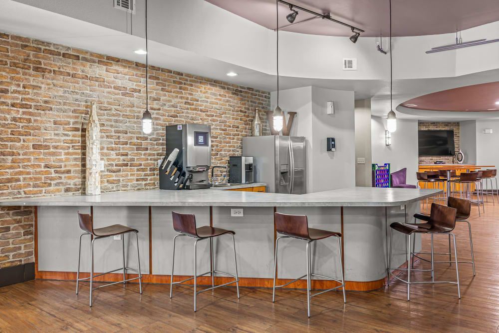 Apartment community kitchen with a long island and stools and a brick wall at Regents West at 26th in Austin, TX, near UT Austin.