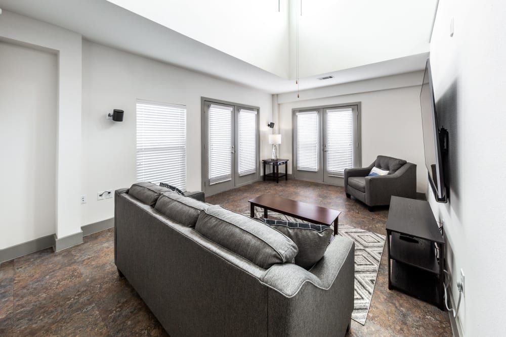 Apartment living room with a couch, chair, coffee table and television at Regents West at 26th in Austin, TX, near UT Austin.