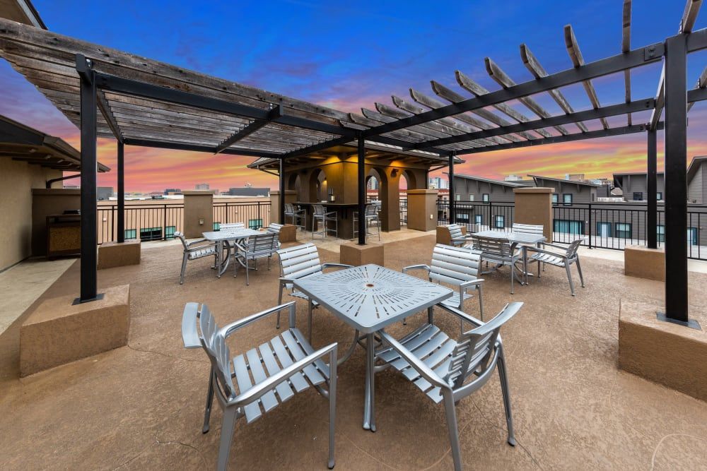 Rooftop terrace with tables and chairs under a pergola at sunset at Regents West at 26th in Austin, TX, near UT Austin.