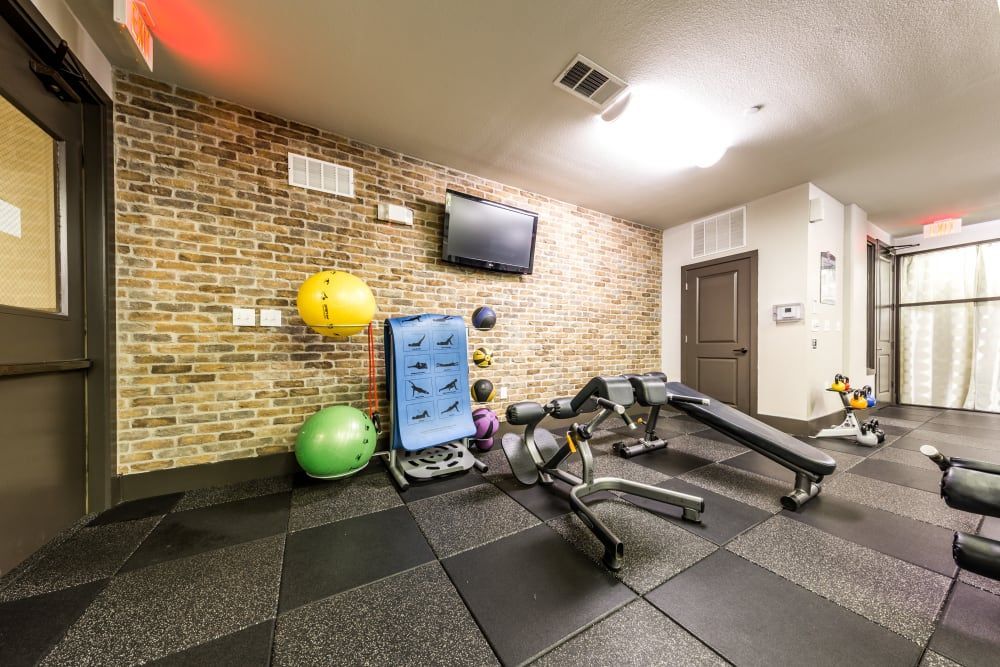 Fitness center with a brick wall and a tv on the wall at Regents West at 26th in Austin, TX, near UT Austin.