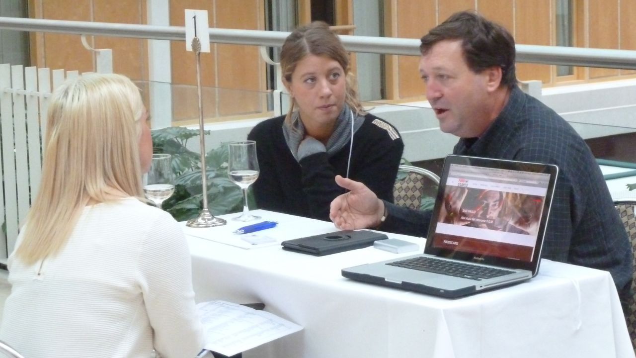 A man and a woman are sitting at a table with a laptop on it