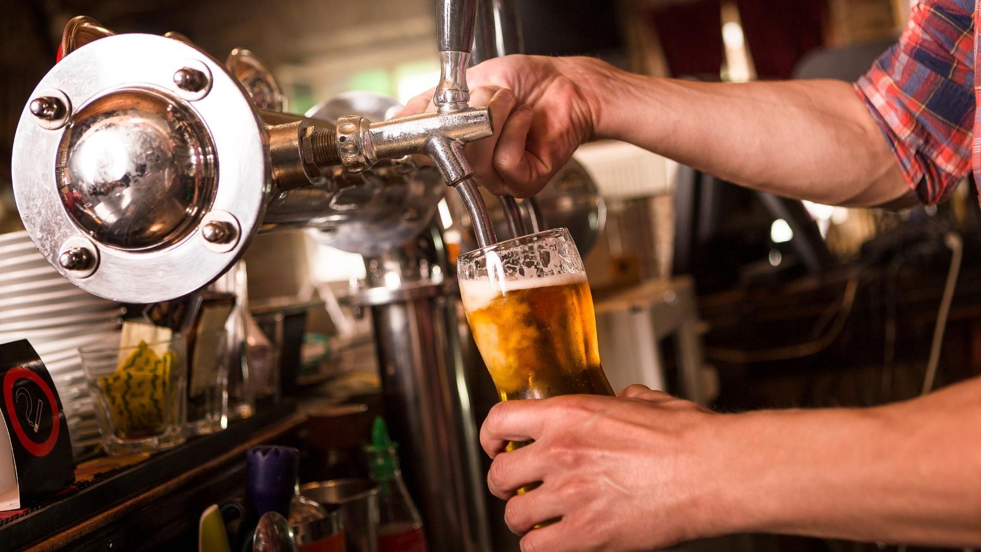 A man is pouring beer into a glass at a bar.