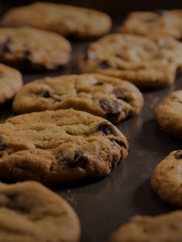 Close-up of freshly baked chocolate chip cookies on a baking sheet.