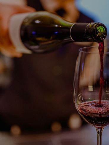 Wine being poured from a green bottle into a clear glass, indoors.
