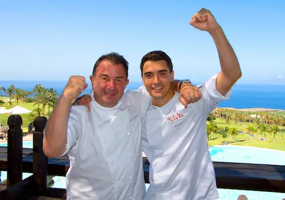 Two men standing next to each other with their arms in the air