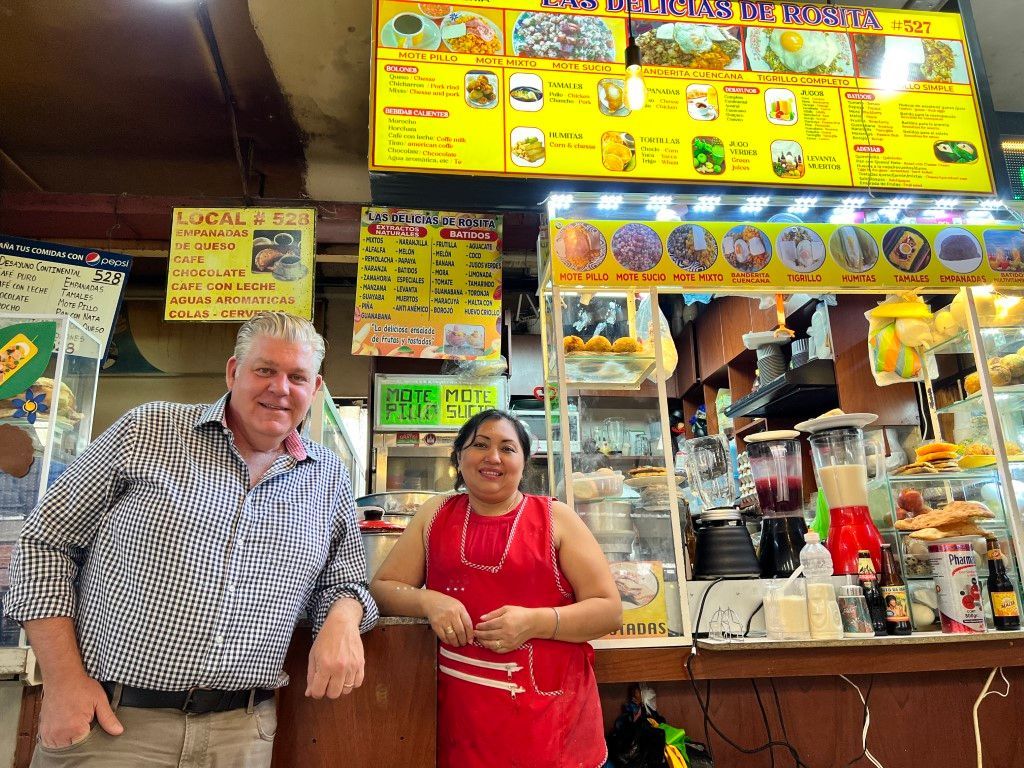 A man and a woman are standing in front of a restaurant counter.