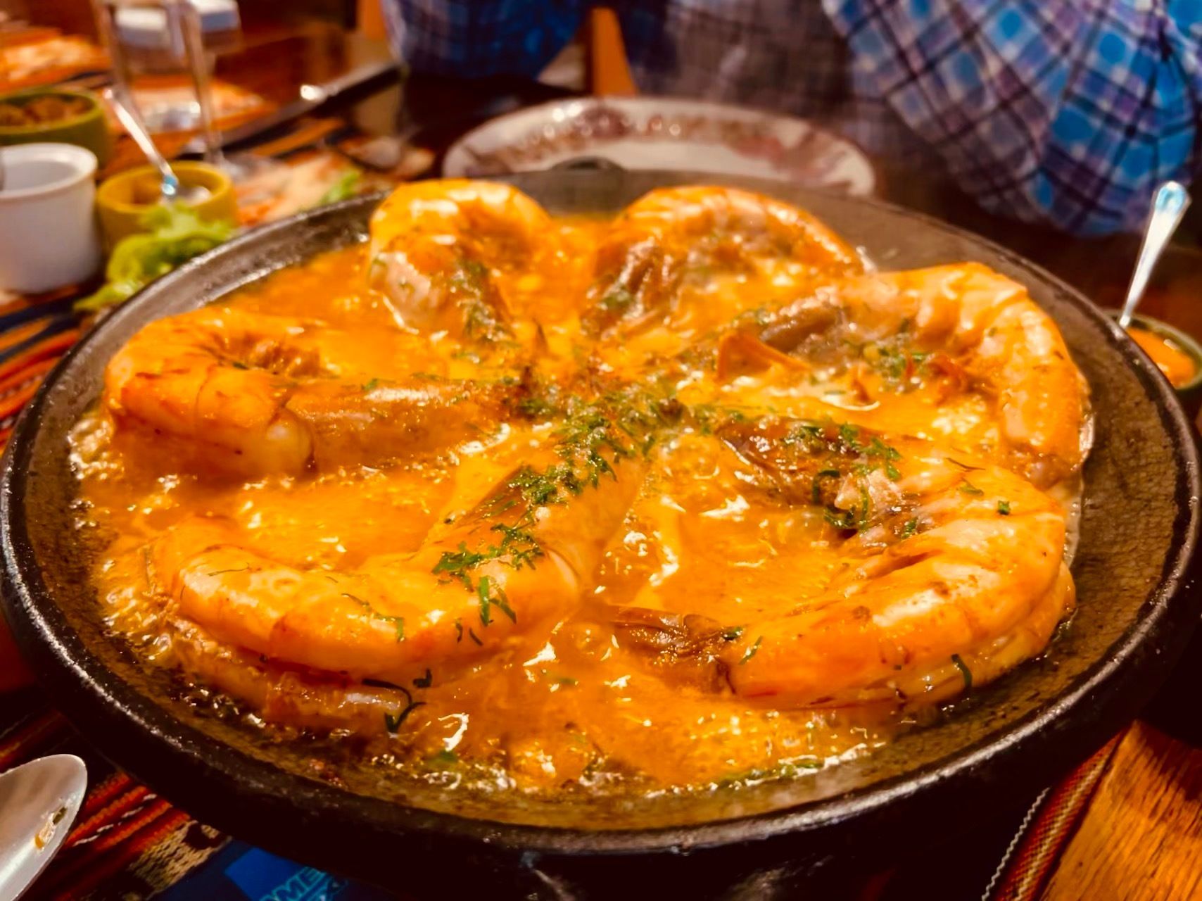 A pan filled with shrimp in a sauce on a table.