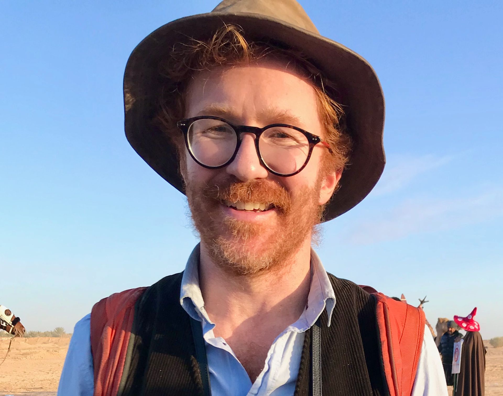 A man wearing a hat and glasses is smiling for the camera