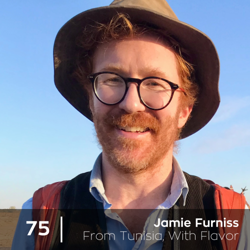 A man wearing a hat and glasses is smiling for the camera