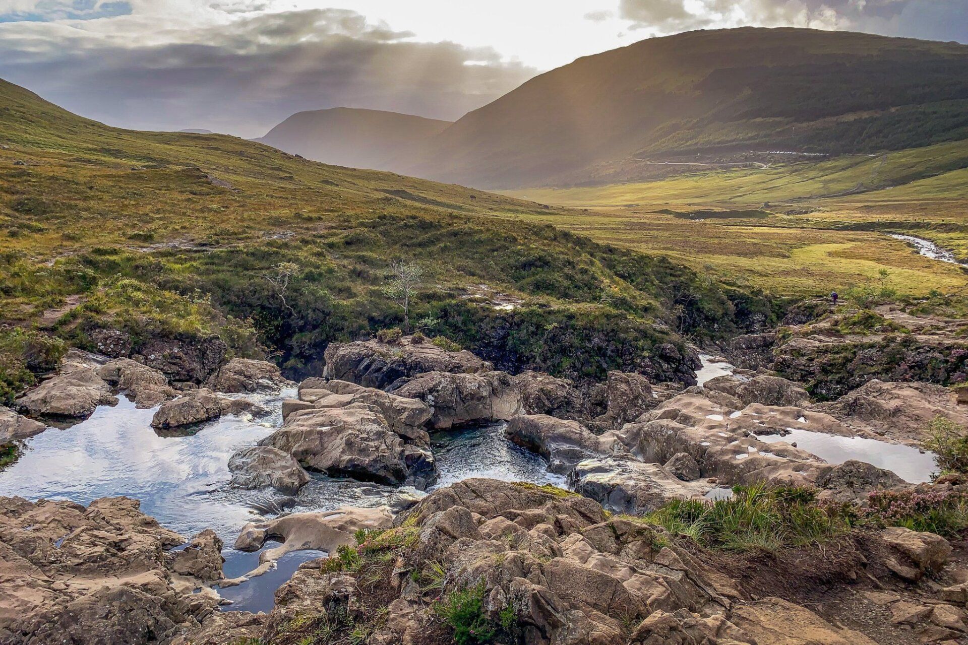 A river flowing through a rocky valley with mountains in the background.