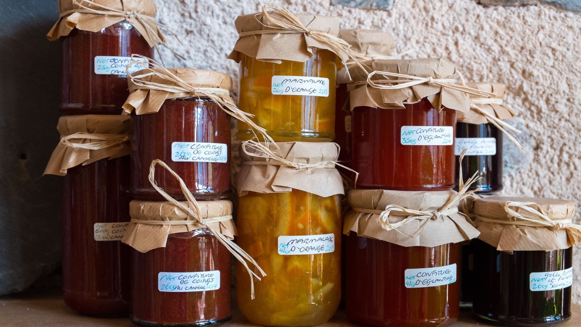 A bunch of jars of jam are stacked on top of each other on a table.