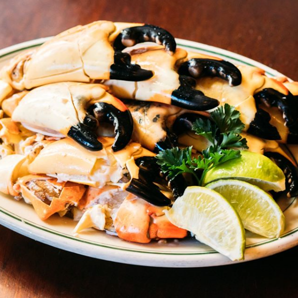 A white plate topped with crab claws and lime wedges