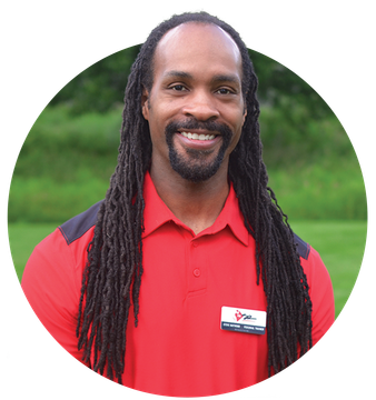 A man with dreadlocks and a beard is wearing a red shirt