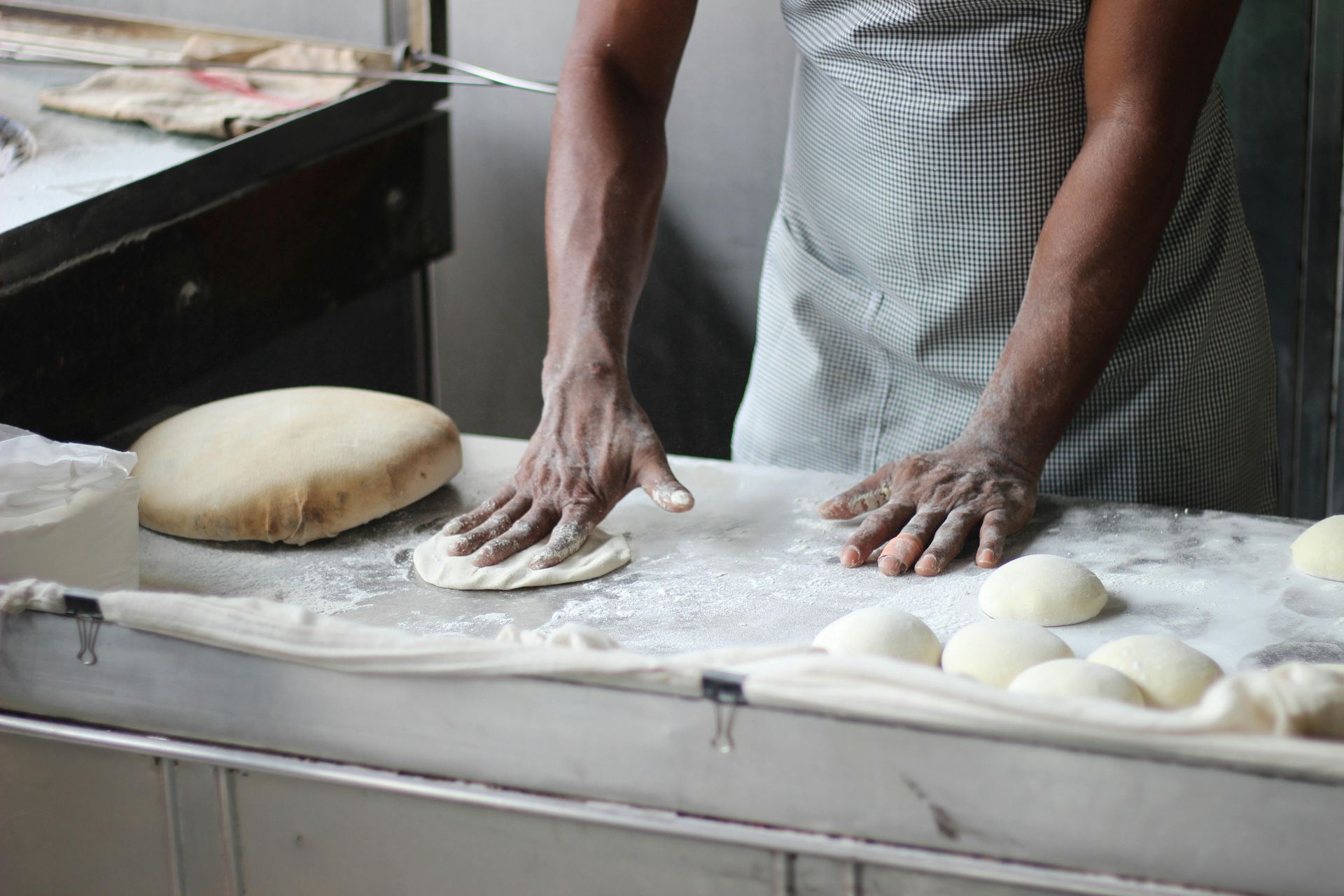 A person is kneading dough on a counter in a kitchen.