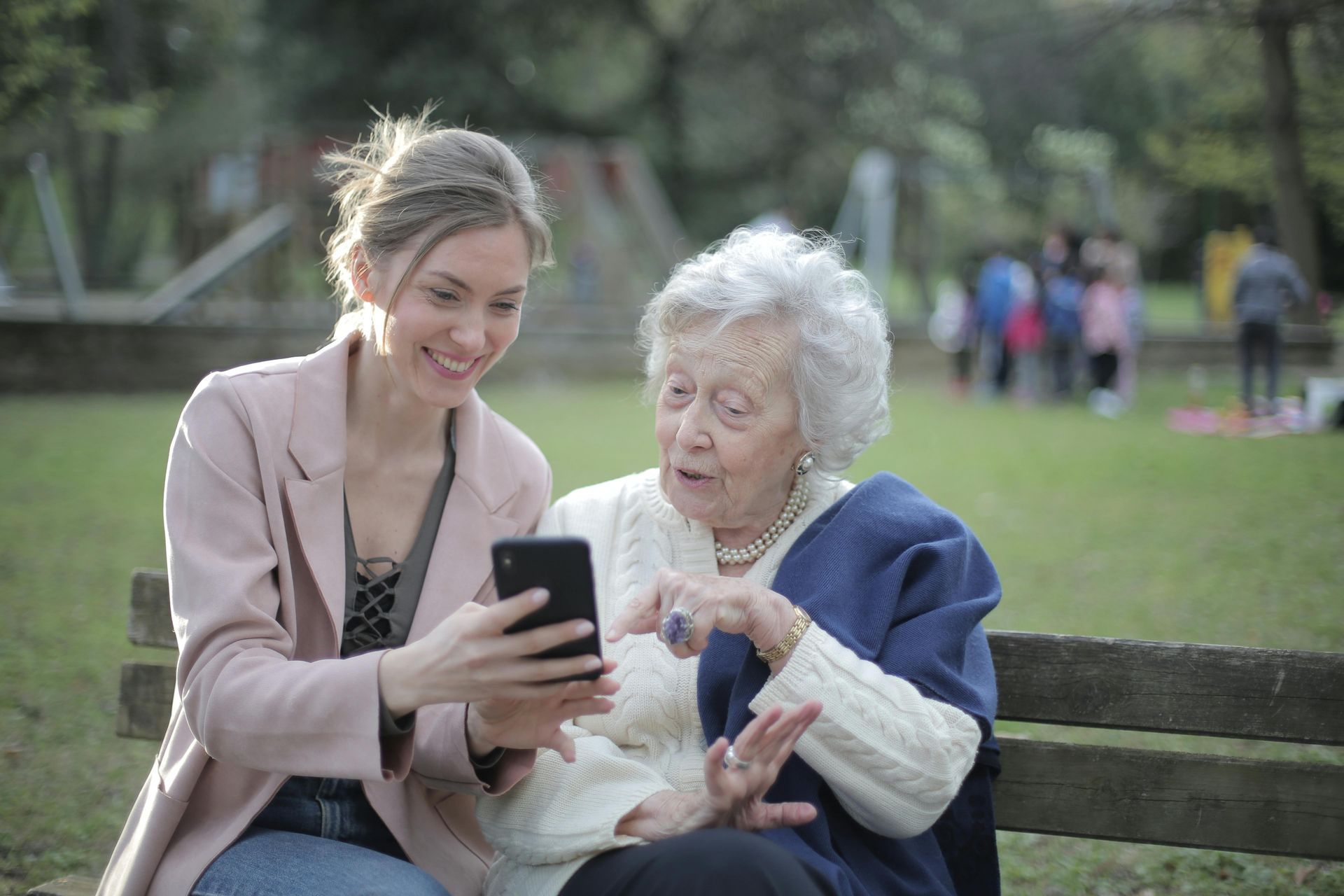 A young woman is showing an older woman how to use a cell phone.