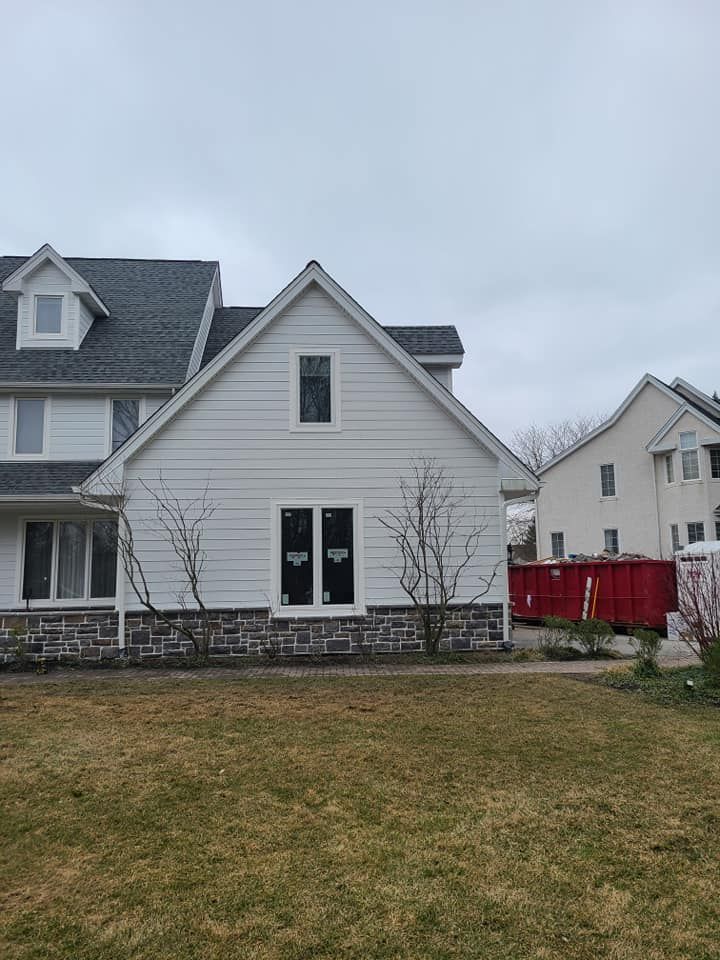 A white house with a red dumpster in front of it.