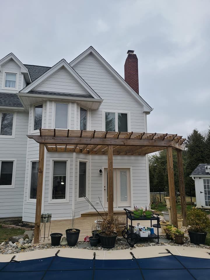 A large white house with a wooden pergola over a pool.